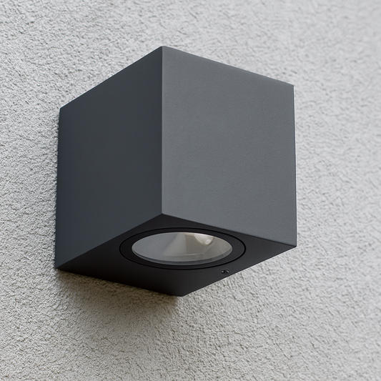 Eine moderne schwarze Wandleuchte in kubischer Form, montiert an einer weißen Hausfassade, geeignet für Außenbereiche.