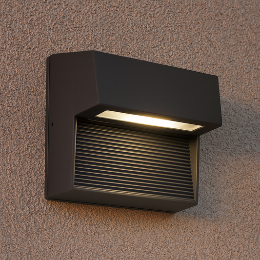 Graue LED-Außenwandleuchte mit Rippengitter an einer Hauswand bei Tageslicht