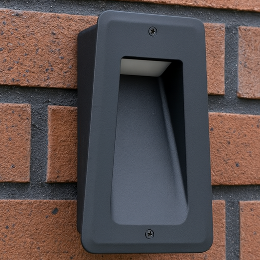 Schwarze LED Einbauwandleuchte mit schrägem Lichtaustritt an einer Ziegelfassade montiert